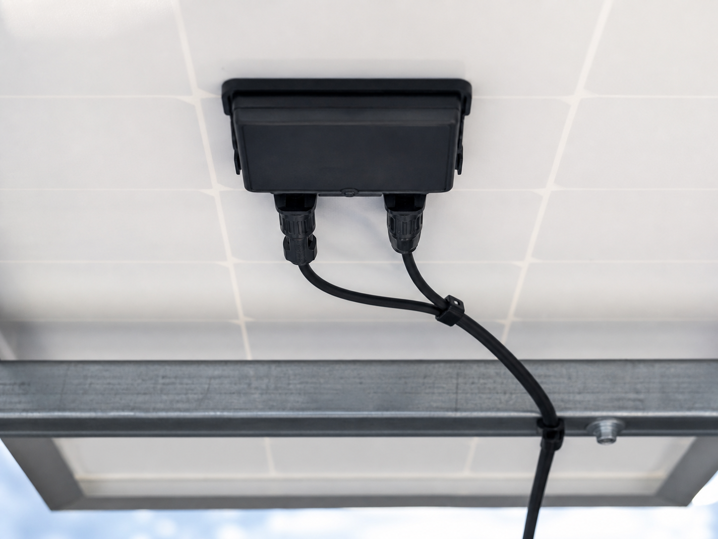PV module junction box with routed DC cable beneath a solar panel